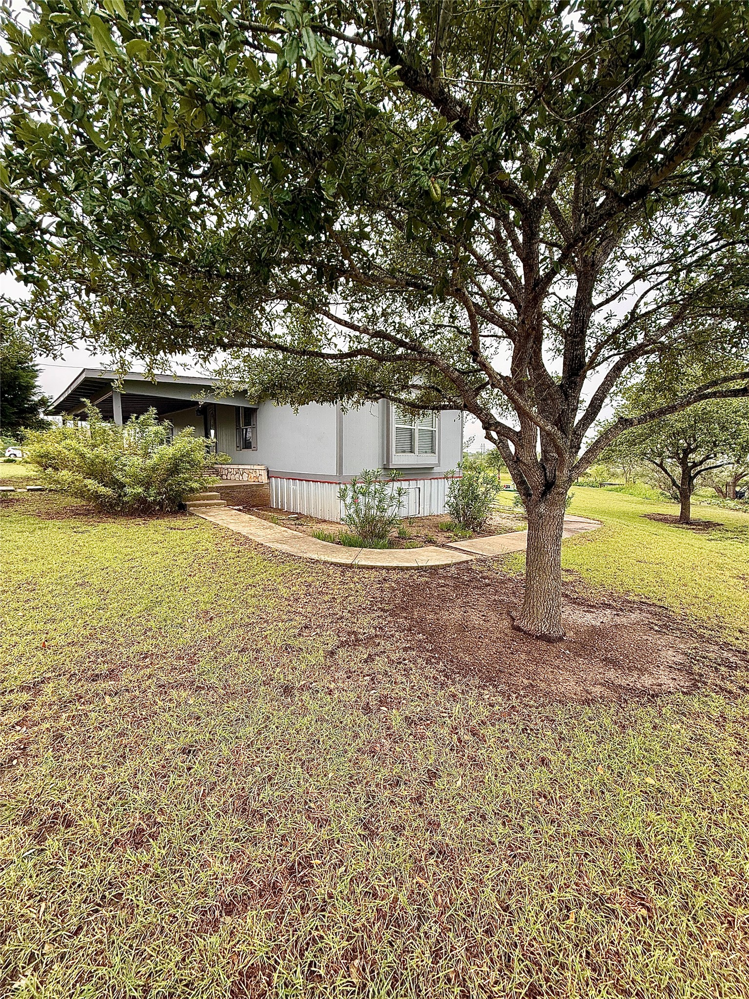 3075 FM 2001 Buda, TX 78610 - Photo 25 of 26 Mature trees and lush greenery frame this charming home with an inviting covered porch.