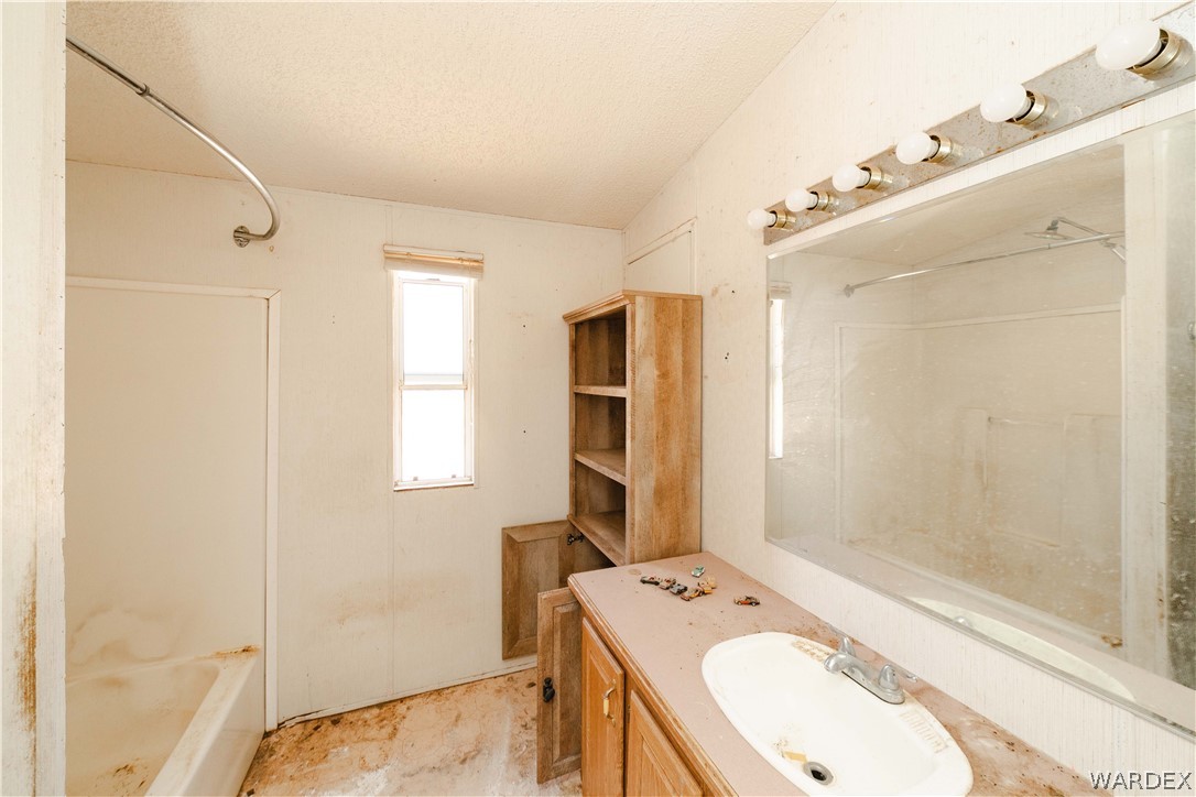 16435 South Wyatt Earp Road Yucca, AZ 86438 - Photo 13 of 57 Bathroom featuring a single window, a built-in vanity with an oval sink, a wall-mounted mirror, and overhead strip lighting