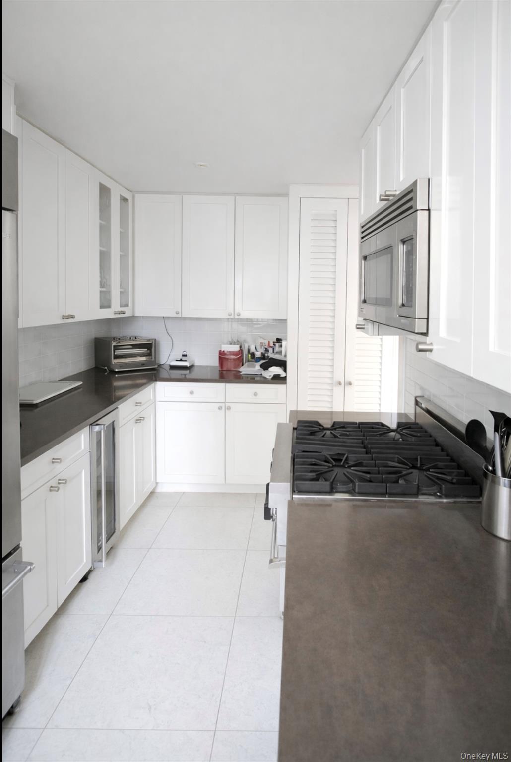 200 East 66th Street, Unit B1503 Manhattan, NY 10065 - Photo 9 of 24 a kitchen with granite countertop a sink a stove and cabinets