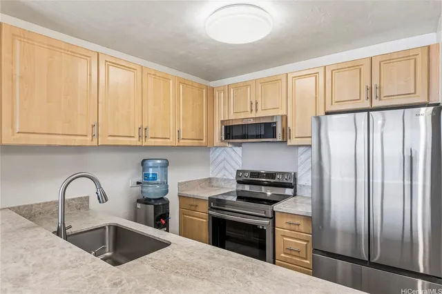 a kitchen with stainless steel appliances granite countertop a stove a sink dishwasher a refrigerator and a microwave oven with wooden floor