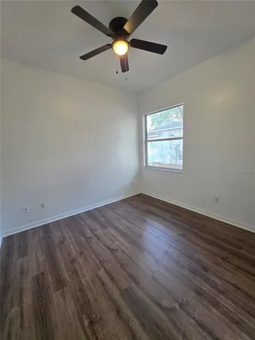a view of empty room with wooden floor and fan