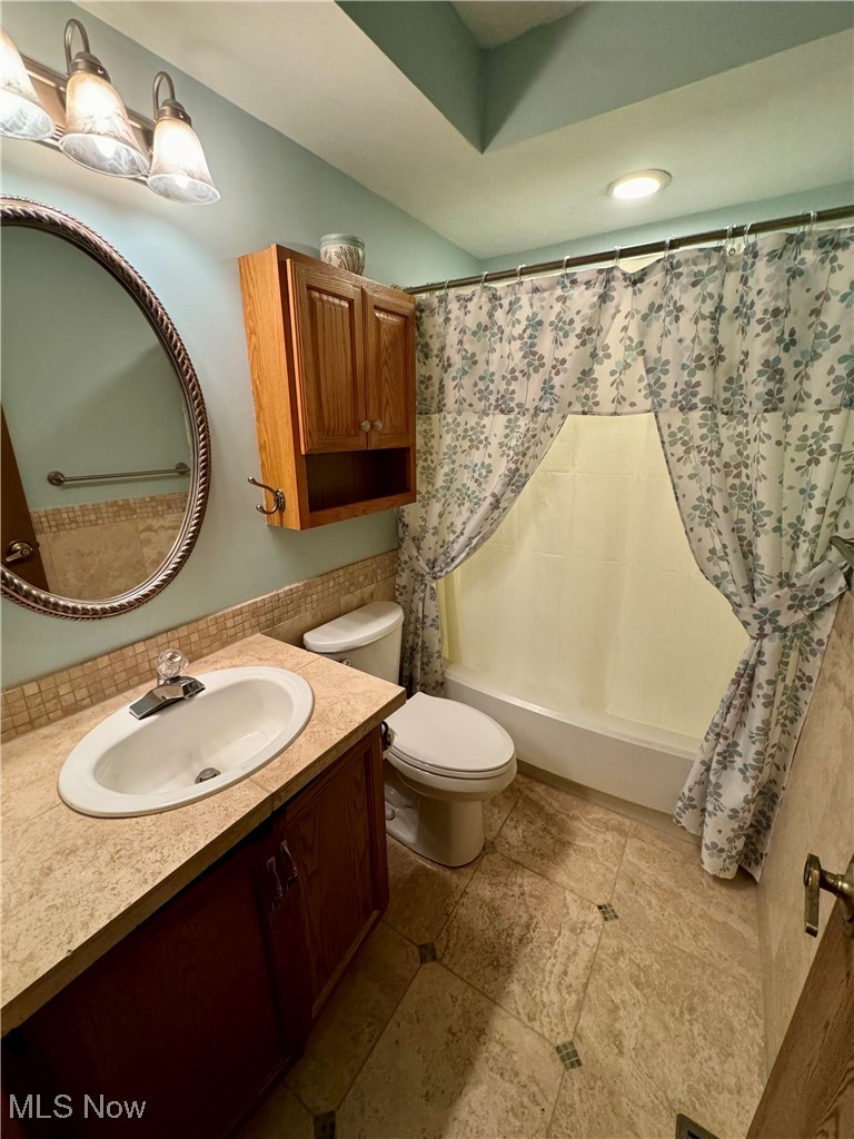 1499 Welch Road Painesville, OH 44077 - Photo 19 of 22 Full bathroom featuring vanity, toilet, tile floors, and shower / bathtub combination with curtain