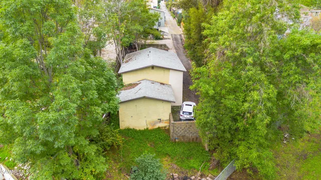 an aerial view of residential houses with outdoor space and trees all around