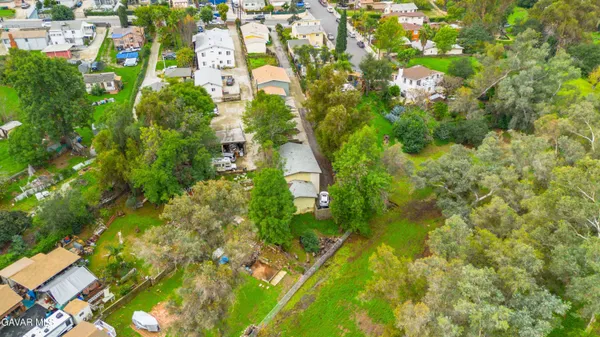 an aerial view of residential houses with outdoor space and trees all around