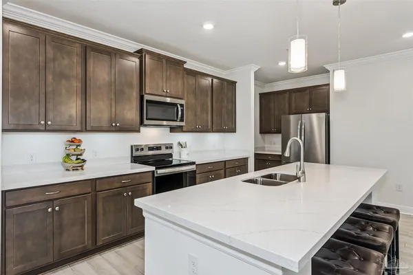 a kitchen with stainless steel appliances granite countertop a stove top oven a sink dishwasher a dining table and chairs with wooden floor