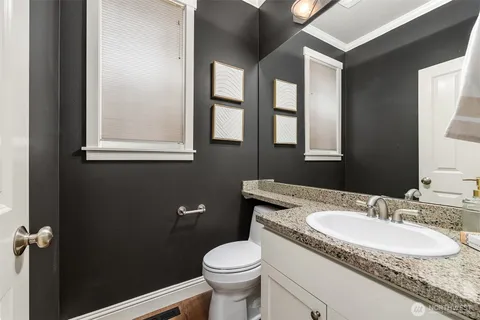 a bathroom with a granite countertop sink toilet and mirror