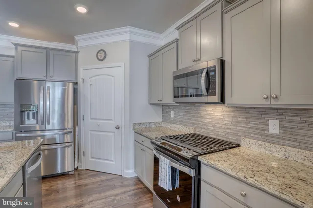 a kitchen with granite countertop a sink stove and refrigerator