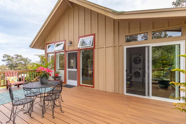 a view of house in front of a big yard with large trees