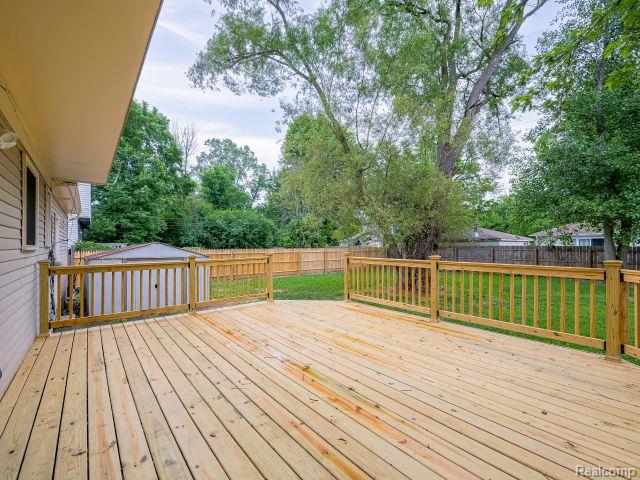 21728 Ruth Street Farmington, MI 48336 - Photo 45 of 54 Spacious wood deck with natural wood railing, overlooking a fenced backyard with mature trees