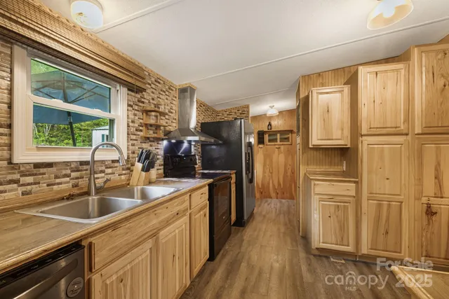 a kitchen with stainless steel appliances granite countertop a refrigerator a sink dishwasher a stove and white countertops with wooden floor