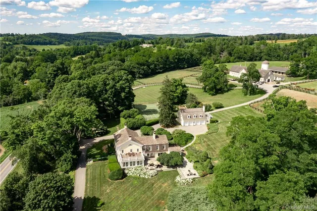 an aerial view of residential house with outdoor space and trees all around