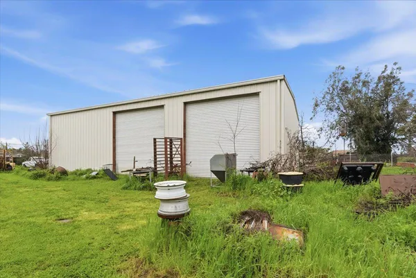 a backyard of a house with table and chairs plants and large tree