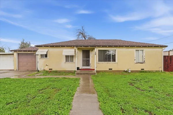 a view of a house with a yard and a large tree