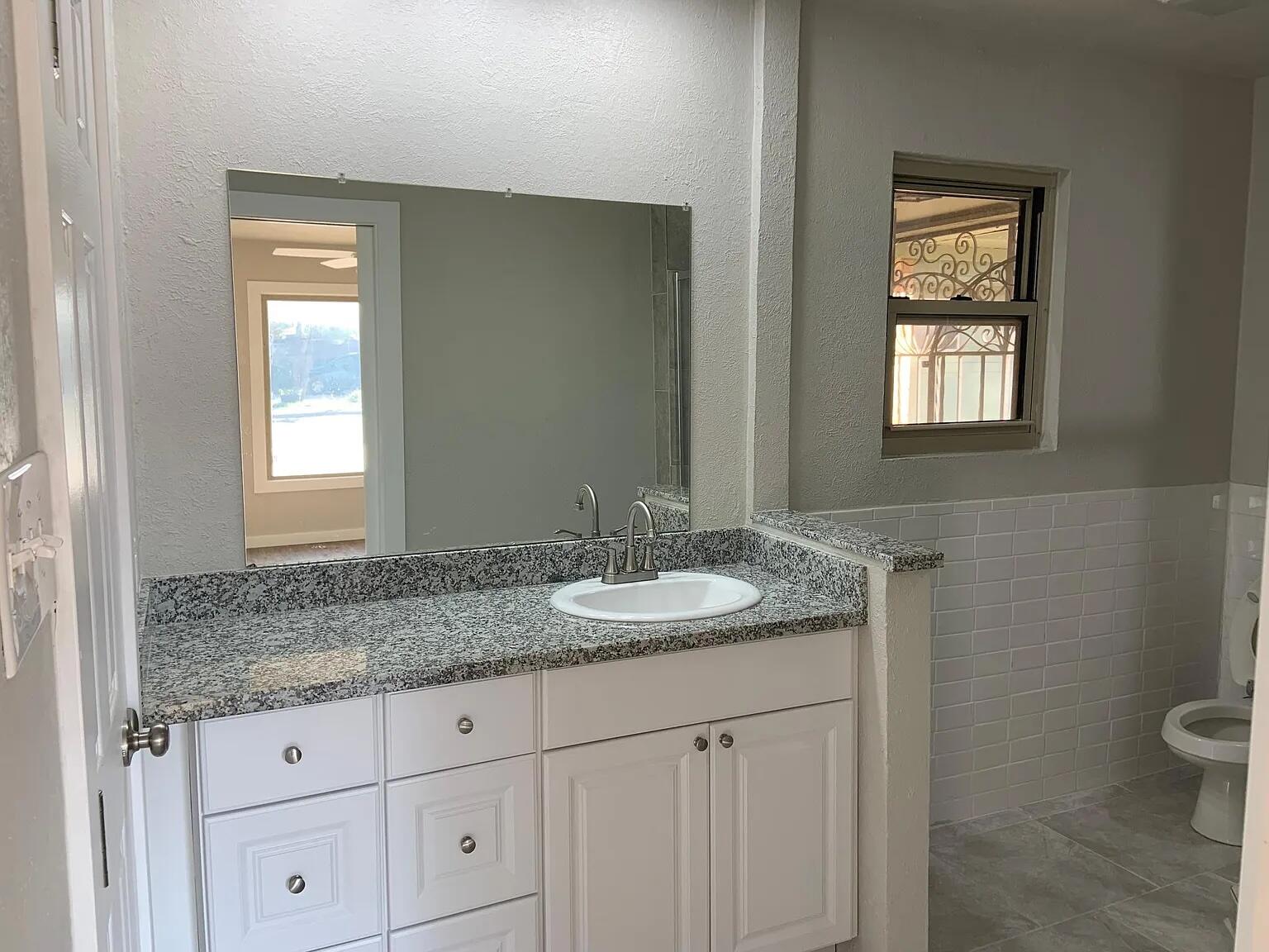 4120 62nd Drive Lubbock, TX 79413 - Photo 16 of 19 a bathroom with a granite countertop toilet sink and mirror