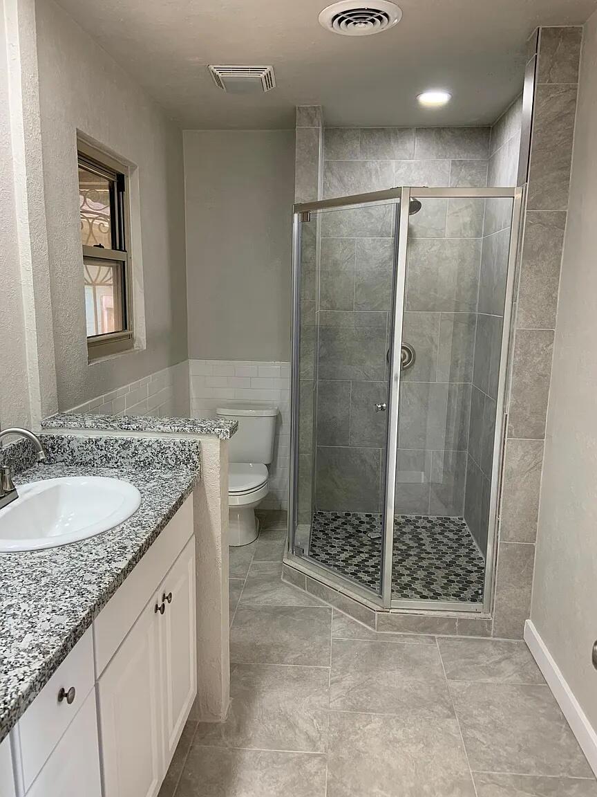 4120 62nd Drive Lubbock, TX 79413 - Photo 17 of 19 a bathroom with a granite countertop sink a mirror a toilet and shower