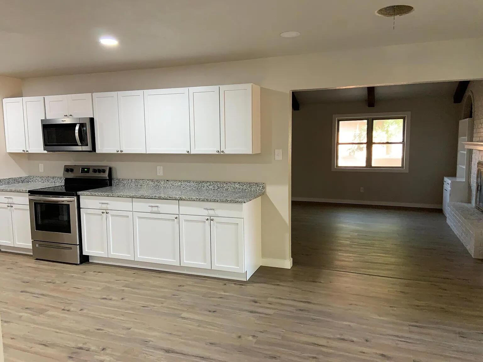 4120 62nd Drive Lubbock, TX 79413 - Photo 5 of 19 a kitchen with granite countertop a stove a sink and a microwave