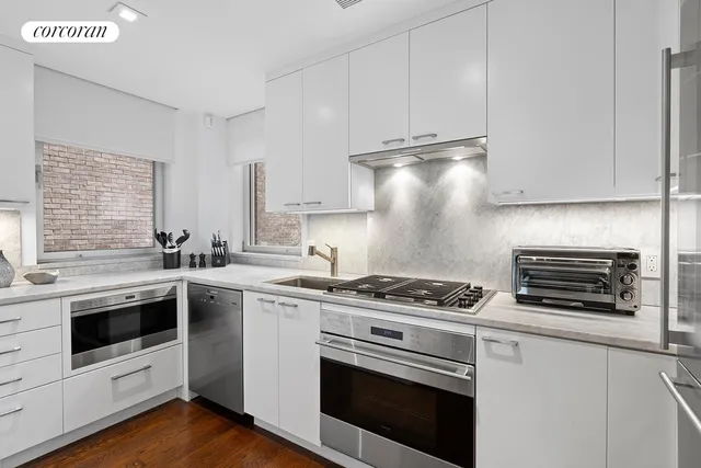 a kitchen with stainless steel appliances white cabinets and a stove top oven