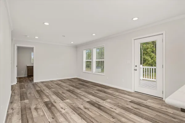a view of an empty room with a window and wooden floor