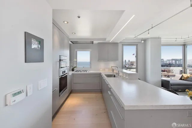 a large white kitchen with a large window a sink and stainless steel appliances