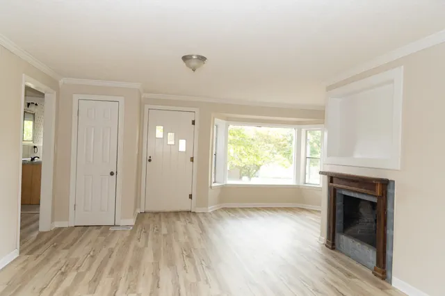 an empty room with wooden floor a fireplace and windows