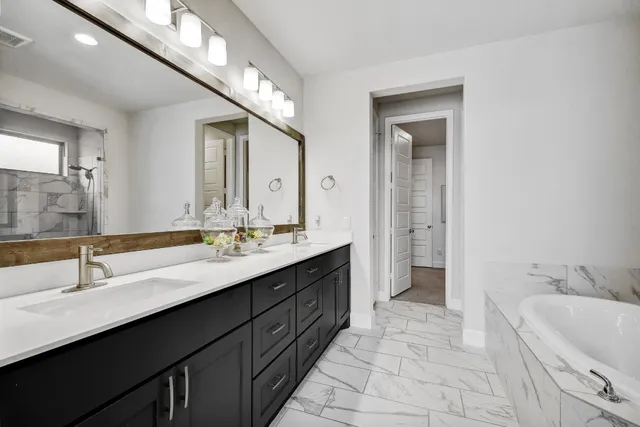 a bathroom with a double vanity sink a mirror and a bathtub