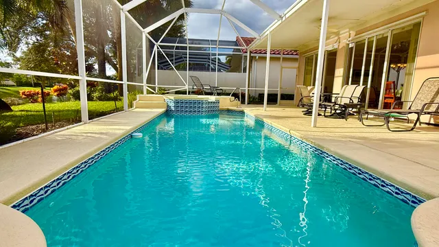 a view of a swimming pool with a yard and palm trees