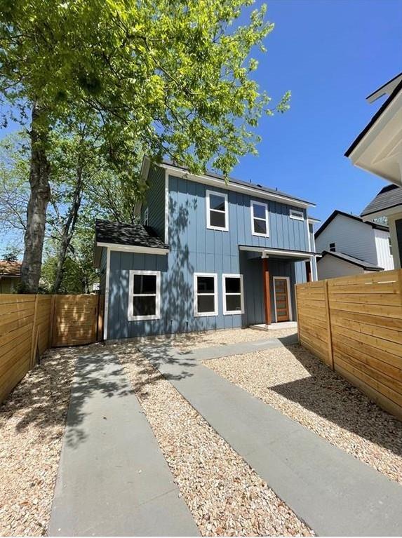 View of front of house with board and batten siding, a fenced backyard, and a patio