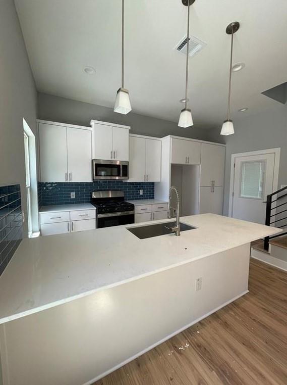 6014 Fairway Street, Unit 2 Austin, TX 78741 - Photo 4 of 20 Kitchen with appliances with stainless steel finishes, wood finished floors, white cabinetry, and backsplash