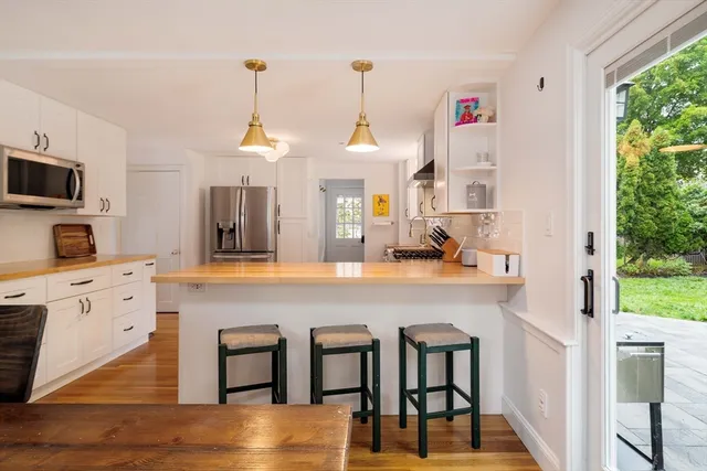 a kitchen with kitchen island a dining table chairs cabinets and a sink