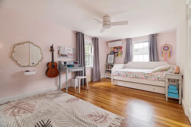 a bedroom with a bed and dresser with wooden floor
