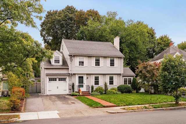 a aerial view of a white house with a yard and large trees