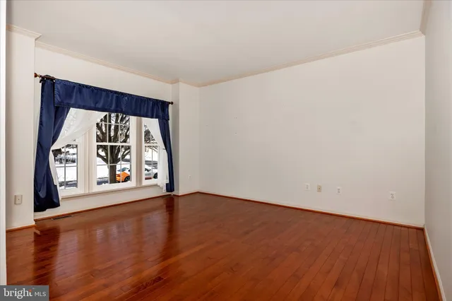 a view of an empty room with window and wooden floor