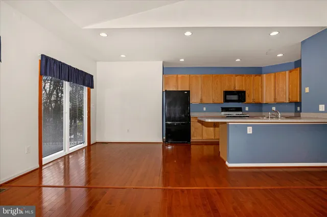 a view of kitchen with stainless steel appliances wooden floor and chair