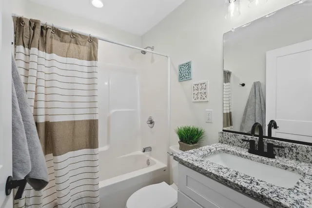 a bathroom with a granite countertop tub sink and mirror
