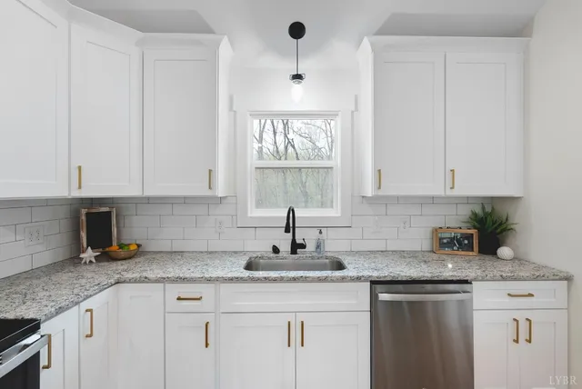 a kitchen with granite countertop a sink white cabinets and a window