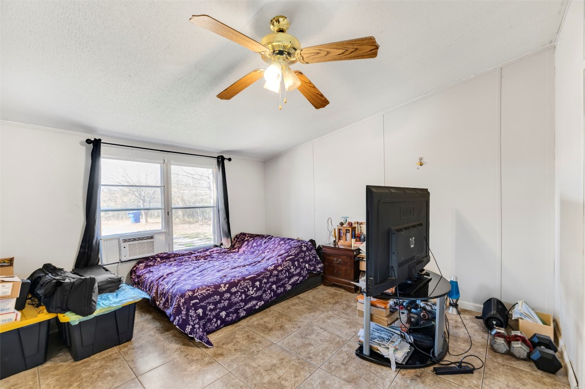 214 The Ranch Road Del Valle, TX 78617 - Photo 13 of 40 a bedroom with bed a flat tv screen and a chandelier