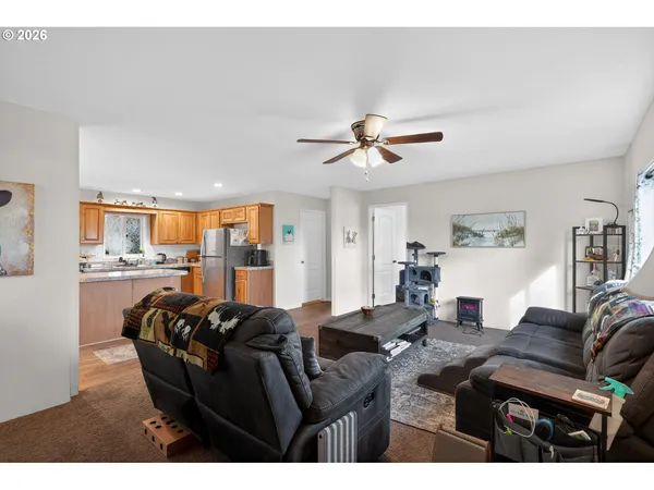 a living room with furniture a ceiling fan and a view of kitchen
