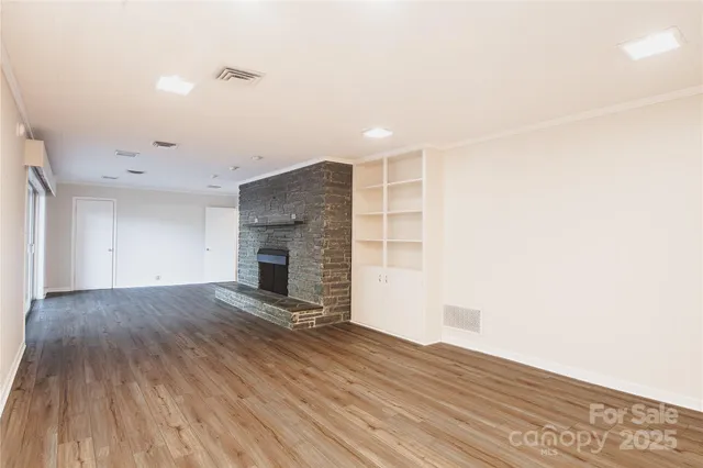 a view of empty room with wooden floor and fireplace