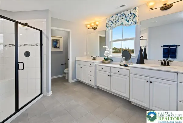 a spacious bathroom with a double vanity sink a mirror and shower