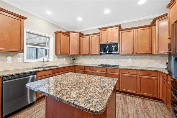 a kitchen with stainless steel appliances granite countertop a refrigerator a sink dishwasher a stove and white countertops with wooden floor