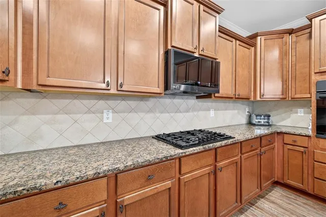 a kitchen with stainless steel appliances granite countertop a refrigerator a sink dishwasher a stove and white countertops with wooden floor