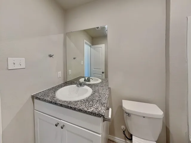 a bathroom with a granite countertop toilet sink and mirror