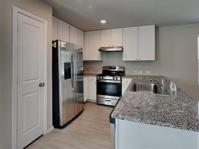 a kitchen with stainless steel appliances granite countertop a stove refrigerator sink and cabinets