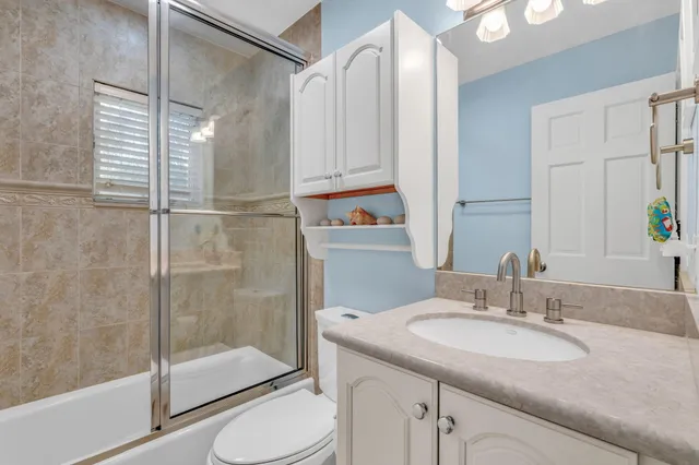 a bathroom with a granite countertop sink toilet and shower