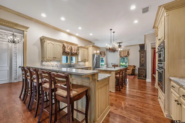 a kitchen with stainless steel appliances kitchen island granite countertop a table chairs sink and cabinets