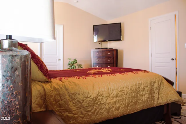 a bed sitting in a bedroom next to a flat screen tv