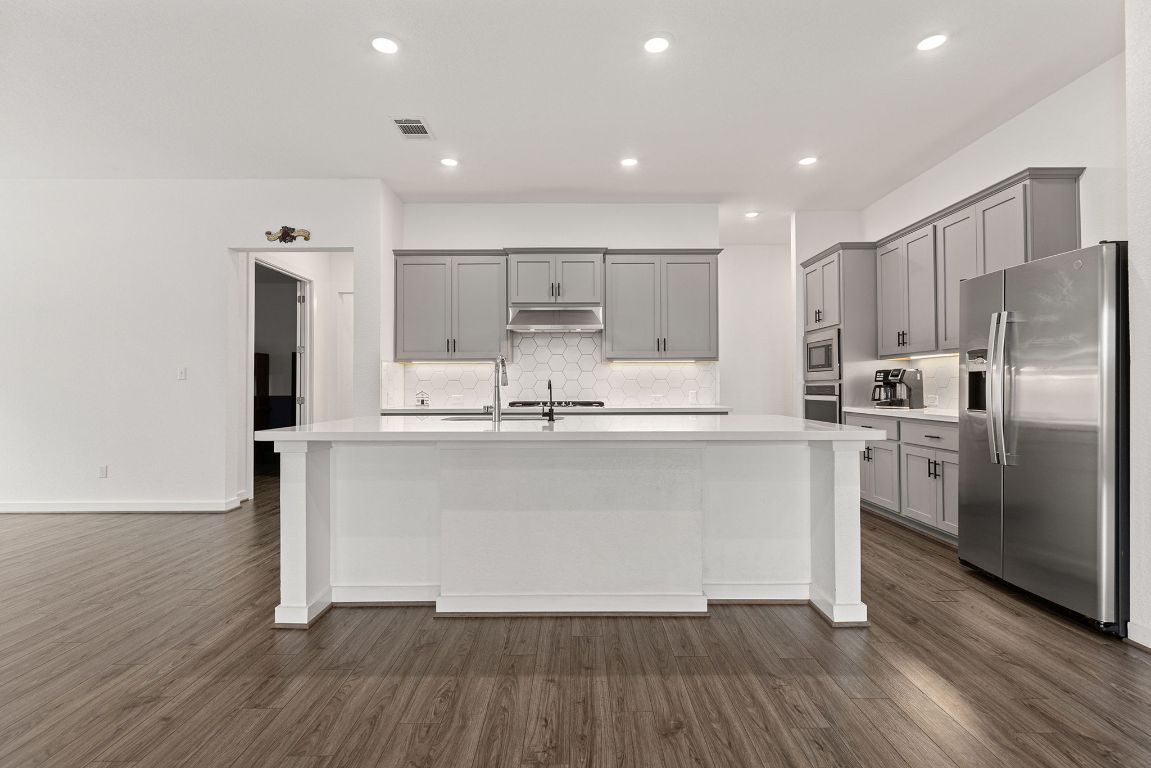 317 Independence Drive Kyle, TX 78640 - Photo 15 of 40 Recessed lighting highlights every detail, from the deep sink to the matte black hardware, tying the whole look together.