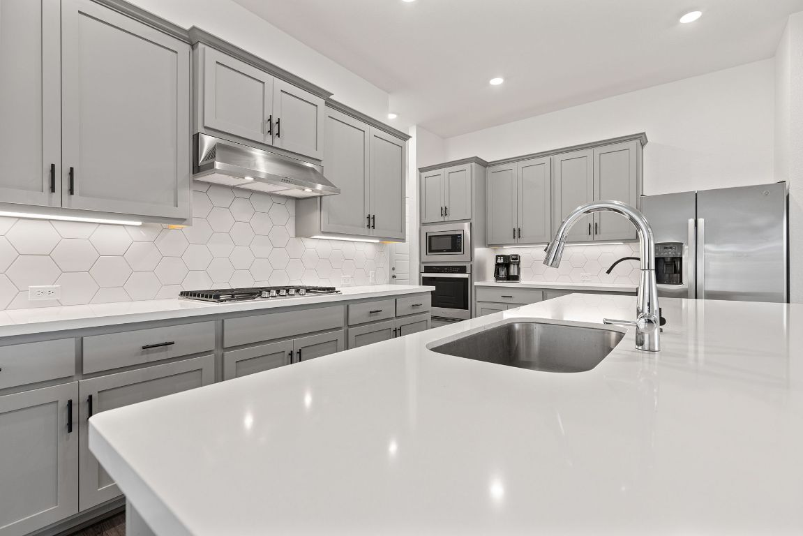 317 Independence Drive Kyle, TX 78640 - Photo 16 of 40 The oversized island is the centerpiece, wrapped in crisp white quartz that practically sparkles under the recessed lighting.