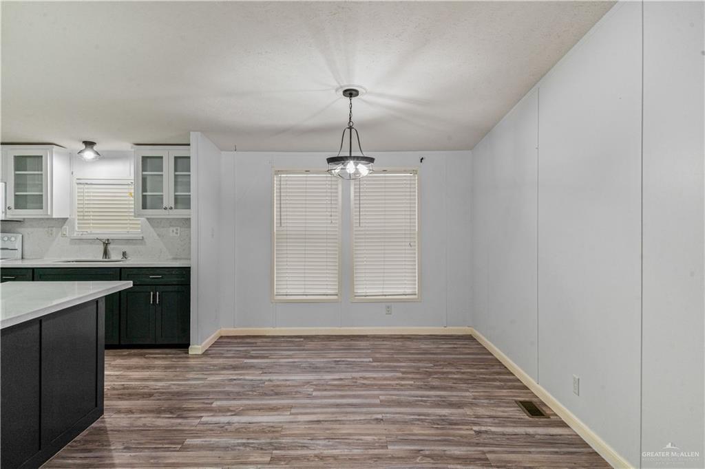 215 South Valley View Road, Unit 252 Donna, TX 78537 - Photo 5 of 19 Open concept living space featuring wood-finish flooring, light gray walls, and a contemporary chandelier