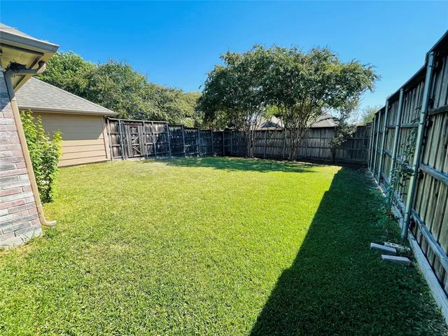 a view of a backyard with large trees and wooden fence